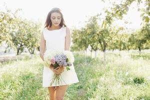 bela jovem usando um vestido branco elegante e curtindo uma bela tarde de sol em um jardim de verão