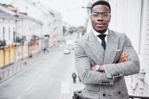 Homem de negócios negro confiante em um terno elegante em um prédio de escritórios olhando para a câmera com uma expressão séria