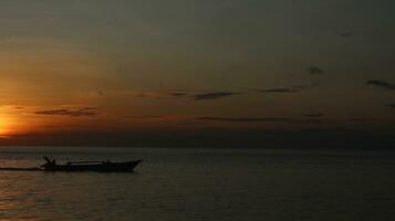 silhueta do uma barco em a mar às pôr do sol foto