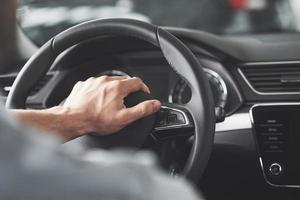 mãos grandes do homem no volante enquanto dirige um carro. foto