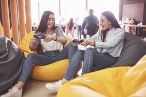 irmãs gêmeas jogam no console. meninas seguram joysticks nas mãos e se divertem foto