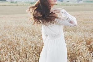 linda garota em um campo de trigo em um vestido branco, uma imagem perfeita no estilo de vida foto