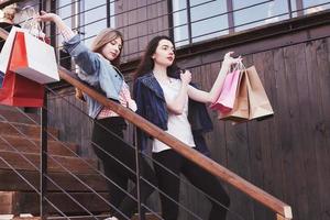 duas jovens carregando sacolas de compras enquanto caminha na escada após visitar as lojas foto