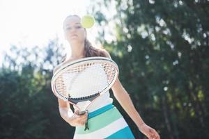 mulher em roupas esportivas serve bola de tênis.