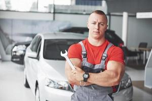 mãos do mecânico de automóveis com a chave inglesa na garagem foto