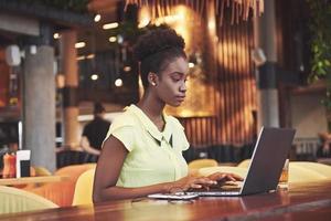 bela jovem sentada em um café e trabalhando em um laptop