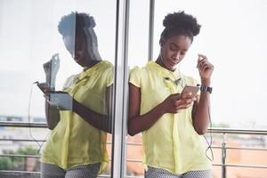 retrato de uma jovem negra atraente com telefone celular e fones de ouvido enquanto ouve música