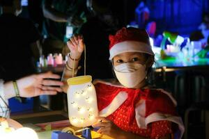 pais e filhos gostam de passar a véspera de natal juntos, fazendo enfeites de árvore de natal. linda garota brincando com luzes de natal foto