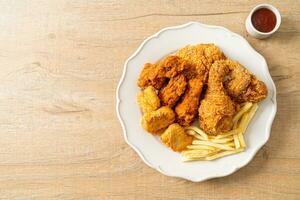 frango frito com batatas fritas e nuggets no prato foto