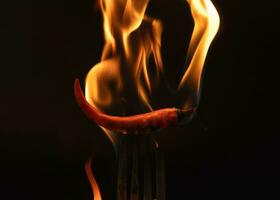 Pimenta Pimenta em garfo com chamas em Preto fundo. queimando vermelho Pimenta Pimenta. lento movimento foto