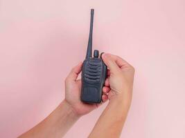 fechar acima mão segurando portátil walkie talkie isolado em Rosa fundo. Preto portátil walkie talkie foto
