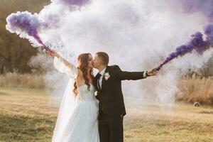 noivas jogar com colori fumaça dentro roxa mãos. fumaça bombas às uma casamento. foto