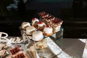 festivo sobremesa mesa com doces. Casamento doce bar, vários bolos, chocolates em fica. foto