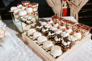 festivo sobremesa mesa com doces. Casamento doce bar, vários bolos, chocolates em fica. foto