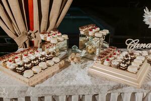 festivo sobremesa mesa com doces. Casamento doce bar, vários bolos, chocolates em fica. foto