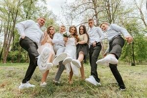 Casamento andar dentro a floresta. noivas e seus amigos pose contra a fundo do a floresta. uma ampla grupo do pessoas estão tendo Diversão às seus amigos' Casamento foto