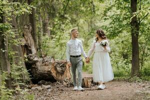 Casamento andar dentro a floresta. a noivo detém a mão do a noiva e elas andar dentro frente do ampla árvores olhando às cada de outros foto