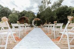 a Casamento arco dentro a parque é fez do fresco flores e seco juncos. longe Casamento cerimônia. branco cadeiras para a cerimônia foto