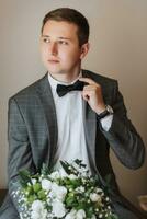 a atraente jovem homem poses Como uma noivo antes uma casamento. a noivo é preparando para a Casamento dentro uma ampla construção foto