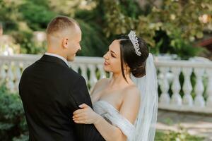 retrato do uma jovem lindo Casamento casal dentro a jardim, a noiva dentro a Fora do ombro Casamento vestir, a noivo dentro uma Preto clássico terno foto