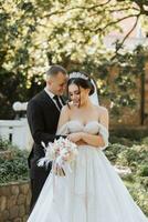 europeu Casamento casal dentro a parque. a noiva dentro uma lindo vestir com uma grandes trem e mangas. noivo dentro uma clássico terno foto