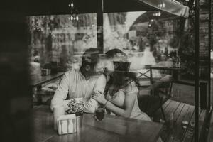 lado Visão retrato do uma amoroso europeu casal rindo enquanto desfrutando uma encontro dentro uma cafeteria. Preto e branco foto