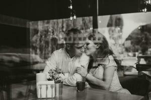 lado Visão retrato do uma amoroso europeu casal rindo enquanto desfrutando uma encontro dentro uma cafeteria. Preto e branco foto