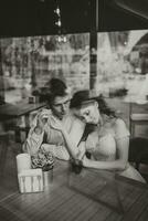 lado Visão retrato do uma amoroso europeu casal rindo enquanto desfrutando uma encontro dentro uma cafeteria. Preto e branco foto