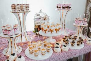 festivo sobremesa mesa com doces. Casamento doce bar, vários bolos, chocolates em fica. foto