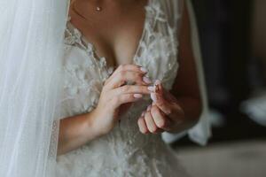 Casamento detalhes. a noiva é vestido dentro uma branco elegante vestir, segurando dela Casamento anel. cortada foto. aberto busto. foto