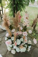 a Casamento arco dentro a parque é fez do fresco flores e seco juncos. ao ar livre Casamento cerimônia dentro natureza dentro uma verde corredor. branco cadeiras para a cerimônia foto