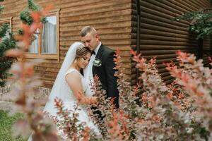 elegante noivo e fofa noiva dentro branco vestir com coroa abraçando dentro parque, jardim, floresta ao ar livre. Casamento fotografia, retrato do sorridente recém-casados. foto