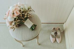 Casamento ramalhete do rosas e vários flores em uma cadeira dentro a Casamento sala. Rosa salto alto mulheres sapatos em a chão foto