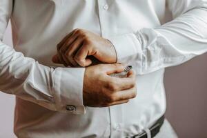 fechar-se do uma homem abotoar dele camisa. a noivo é preparando para a casamento. a homem desgasta uma branco camisa. à moda noivo foto