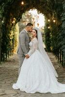 jovem Casamento casal desfrutando romântico momentos ao ar livre em uma verão Prado. uma noiva com uma coroa em dela cabeça e uma grandes véu. noivo dentro uma clássico cinzento terno foto