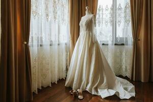 uma luxuoso renda Casamento vestir dentro a caro interior do uma hotel iluminado de natural luz a partir de uma janela em dois lados foto