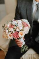 uma à moda noivo é preparando para a Casamento cerimônia dentro a manhã. do noivo manhã. uma homem dentro uma clássico terno e uma arco gravata. jovem e bonito noivo com uma ramalhete do flores foto
