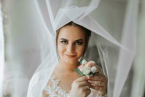 fêmea beleza. fofa mulher às lar. a noiva poses para a fotógrafo. uma à moda mulher desgasta uma branco vestir. profissional Maquiagem e cabelo. em a da noiva cabeça é uma diadema e uma grandes véu. foto