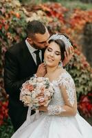 a noiva e noivo dentro a outono parque perto a casa, Casamento cerimônia, frente visualizar. noivo e noiva em a fundo do amarelado outono folhas. foto