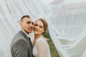 Casamento casal em natureza. noiva e noivo abraçando debaixo a véu às casamento. foto