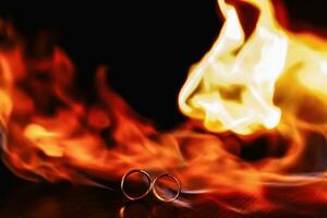 dois Casamento argolas dentro uma chama do fogo em uma Sombrio fundo. casamento. tradições. foto