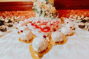 uma doce mesa às uma casamento. mesa com bolos e doces às a festival. aniversário doces foto