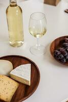 queijo prato com uvas e branco vinho em mesa, fechar-se foto