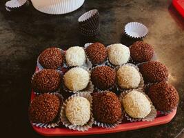 chocolate trufas com branco e Preto listras em vermelho prato foto