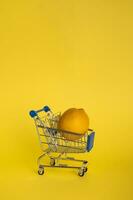 limão dentro uma compras carrinho em uma amarelo fundo. a conceito do a venda do frutas e legumes. foto