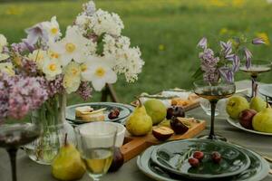 mesa conjunto para uma piquenique dentro a Prado com flores e frutas foto