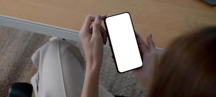 maquete imagem em branco tela branca celular phone.women mão segurando mensagens de texto usando o celular na mesa no escritório em casa. foto