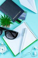 planejamento de férias. acessórios de viagem sobre um fundo azul. passaporte, óculos de sol e bloco de notas. foto