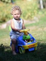 lindo menino com carrinho de brinquedo infantil posando fotógrafo foto