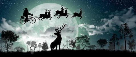 silhueta do Papai Noel andando de bicicleta para carregar um presente com suas renas durante a lua cheia à noite de Natal.